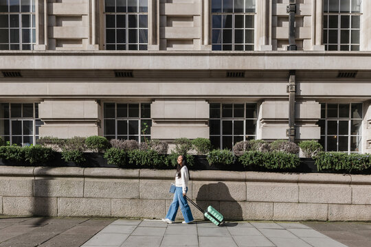 Woman Traveler pulling luggage walking city street preparing journey