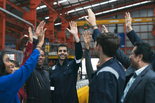 Group of diverse workers join hands together in factory. Team of male and female factory workers at work. Meeting and training at work. Successful of work concept
