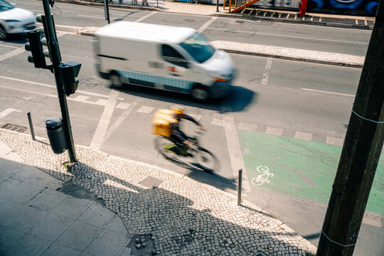 Bicyclist Crosses the Road While Cars Drive Past in the City