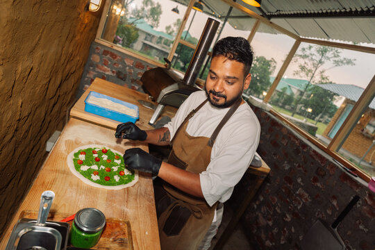Chef Prepares Pizza With Toppings at Outdoor Kitchen in the Evening