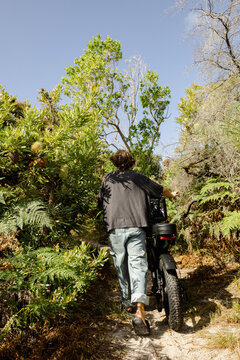 Man walking e bike along narrow coastal nature path