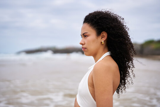 Young woman contemplating ocean on beach vacation
