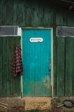 Teal door with welcome sign on rustic wooden shack