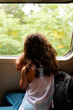 Child Gazing Through Train Window in Motion