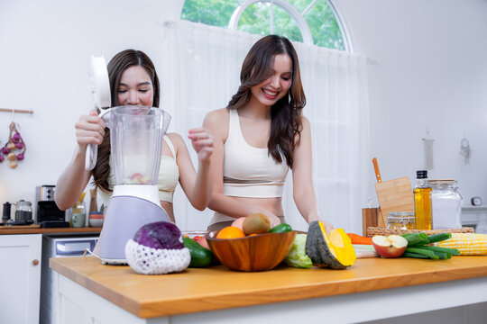 Happy friends preparing nutritious food with fresh vegetables and fruits in a contemporary kitchen highlighting healthy habits natural nutrition and joyful home cooking.

