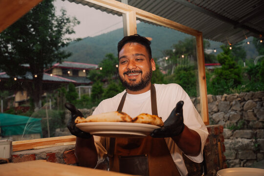 Chef Serves Pizza l in Outdoor Kitchen at Scenic Location