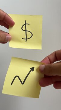 Hand holding sticky notes with dollar sign and growth arrow