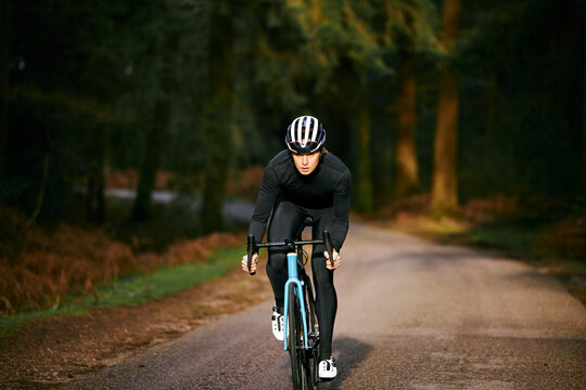 Focused Female Cyclist Training Through Woodland Countryside