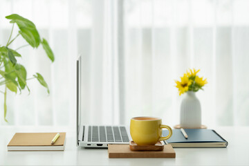 Laptop side view and orange cup with sunflower on white table, minimal home office © paladin1212