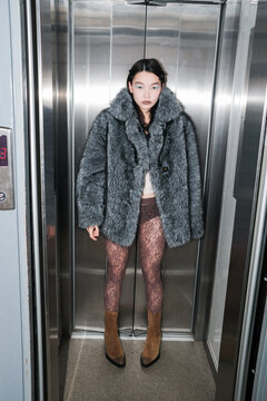 Model Poses in Elevator Wearing Furry Coat and Patterned Tights
