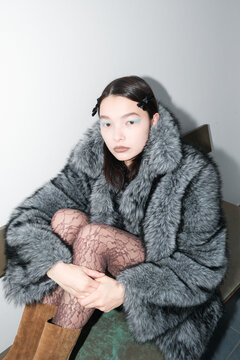 Fashion Model Poses in a Studio Wearing a Fur Coat and Lace Leggings