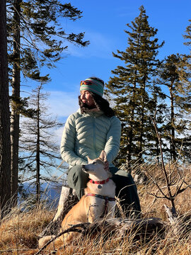 Woman and her dog taking a break on a mountain ridge during a sunny