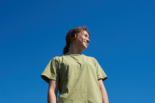 Portrait of teen girl standing against blue sky
