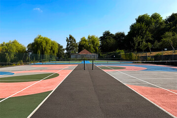 Naklejka premium Vibrant courts burst with colors like pink, green, and blue, while trees and lush greenery wrap around the area, adding to the peaceful vibe of Northcliffe Park in Shipley, Bradford, UK.