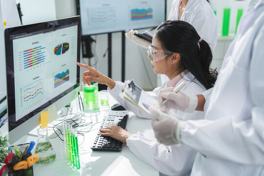 Scientist laboratory computer chart test tube research woman data analysis sample, focused team studying colorful graph and green liquid in modern medical workspace