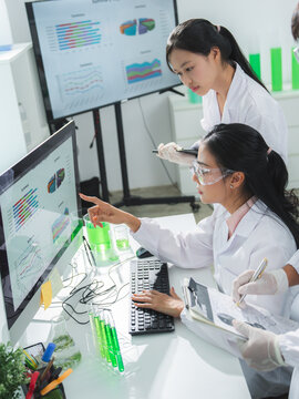 Scientist laboratory woman computer data chart analysis research team with safety goggle studying graph on monitor near test tube for biotechnology experiment