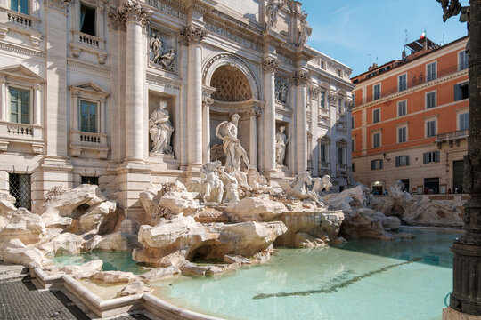 Scenic view of the grand Trevi Fountain with its clear turquoise pool and intricate baroque marble sculptures under a bright sky in Rome, Italy