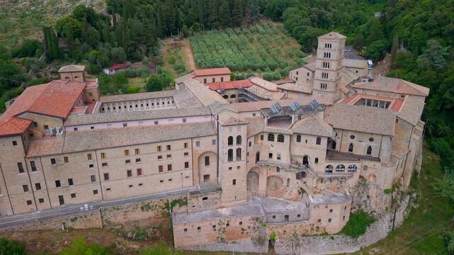 Santa Scolastica Monastery Subiaco Italy 4K Drone. Aerial overflight of historic complex to olive trees field. Ancient medieval abbey in Simbruini mountains scenic b roll cinematic video asset