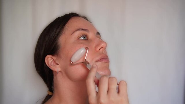Woman Using Pink Jade Facial Roller for Skincare Massage Routine on White Background, Beauty Wellness and Self Care Concept