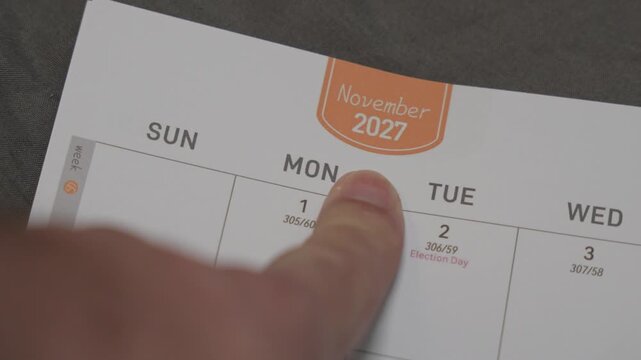 finger pointing at November 2027 planner page close up for scheduling and monthly planning concept