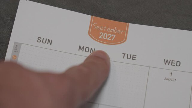 finger pointing at September 2027 planner page close up for scheduling and monthly planning concept
