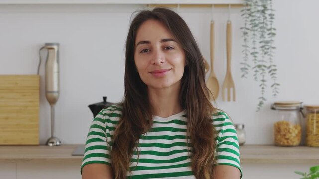 Portrait of young happy Latin American woman smile at camera sitting at kitchen table. People and happiness concept