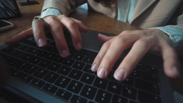Close-up of a young Hispanic businesswoman&rsquo;s hands typing on a laptop while working in a modern office, highlighting productivity, office tasks, and professional workflow.