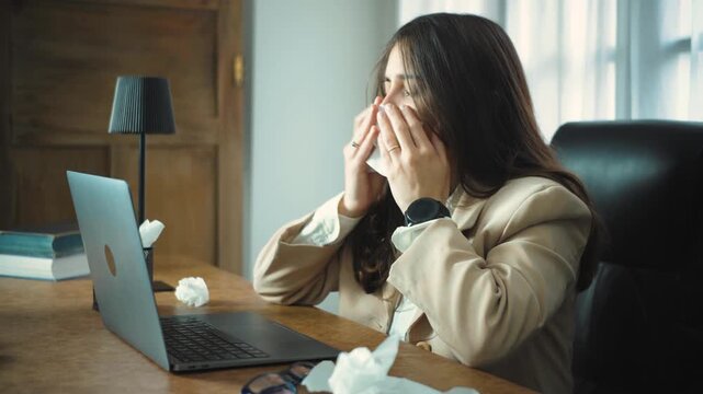 Young Hispanic businesswoman feeling physically unwell while working in her office, checking the time on her watch as she waits to finish her workday and go home.
