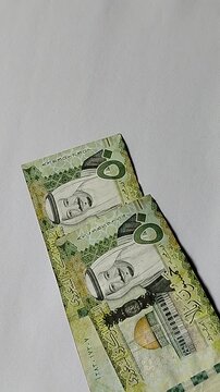 A detailed view of someone counting 50 Saudi Riyal currency notes, highlighting cash payment, financial responsibility, personal budgeting, commerce, investment, remittance, and economic growth.