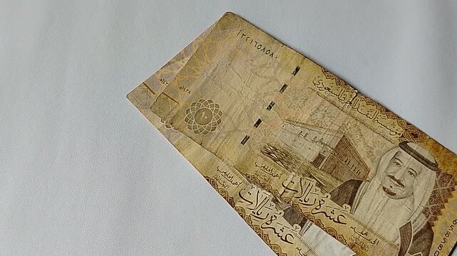 A close-up of a person counting 10 Saudi Riyal banknotes by hand, illustrating cash transactions, financial management, budgeting, personal finance, and everyday economic activities in Saudi Arabia an