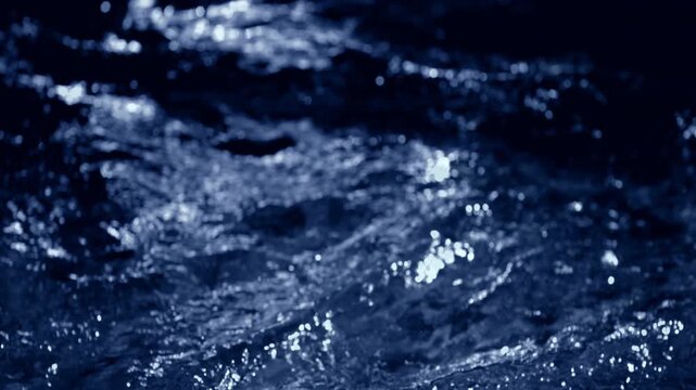 Fresh blue water macro background loop with splashing liquid on dark black backdrop. 3D animation wave fluid swirling backplate with copy space. Clean abstract bubbles texture.