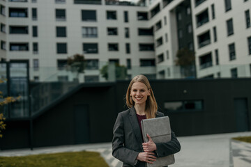 Fototapeta premium Confident business woman smiling in front of city apartment building