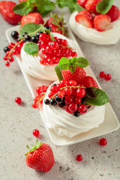 Pavlova dessert with strawberries, black currant, red currant, and mint.