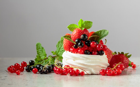 Pavlova dessert with strawberries, black currant, red currant, and mint.