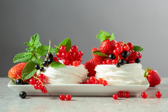 Pavlova dessert with strawberries, black currant, red currant, and mint.