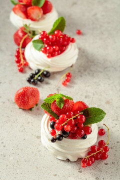 Pavlova dessert with strawberries, black currant, red currant, and mint.
