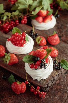 Pavlova dessert with fresh berries and mint on an brown vintage table.