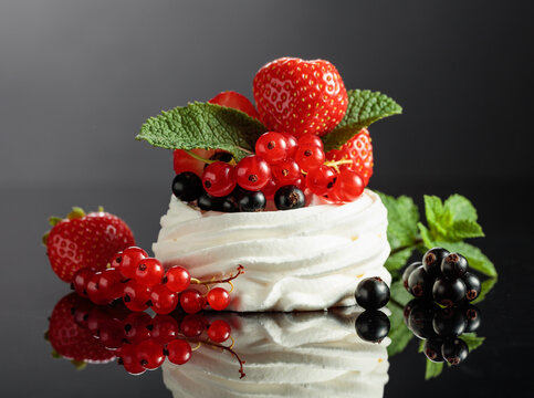 Pavlova dessert on a black reflective background.