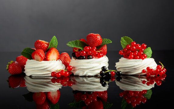 Pavlova desserts on a black reflective background.
