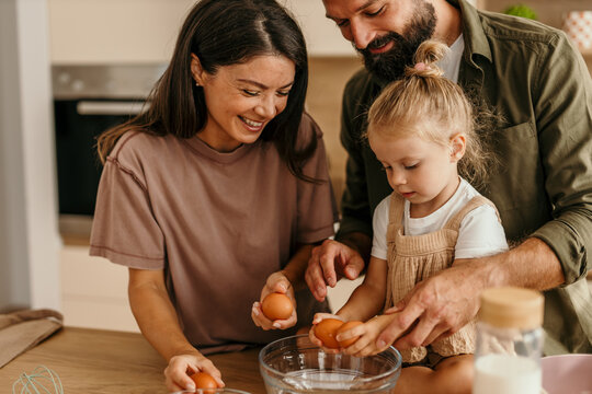 Parents and daughter baking together in kitchen