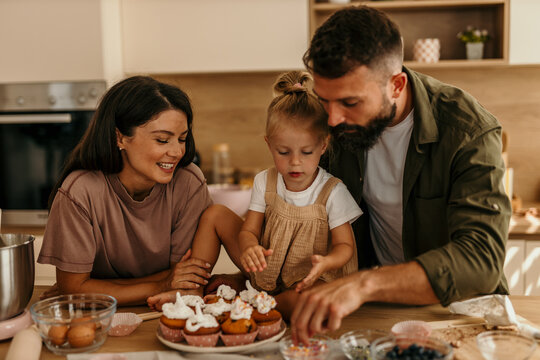 Family baking cupcakes together in modern kitchen