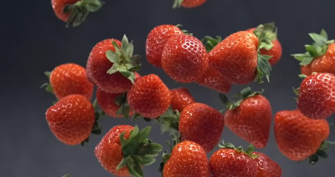 Strawberries falling in super slow motion on black background