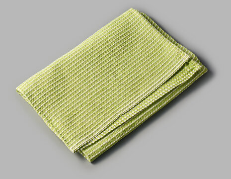 folded green dish towel isolated gray background, textured white striped pattern cleaning cloth, angle view