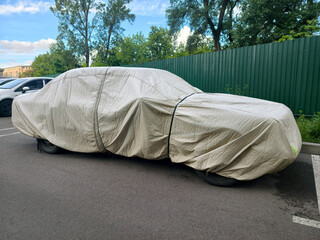 Vehicle in parking lot protected by nylon car cover maintaining cleanliness and exterior quality © Harmony Video Pro