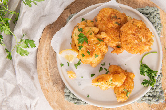 Crispy golden cod fish fritters on a rustic plate with fresh parsley and a lemon slice for a delicious Mediterranean seafood appetizer
