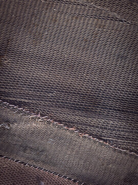 Detailed texture shot of dark traditional fishing net panels layered on top of each other showcasing artisanal nautical craftsmanship and material