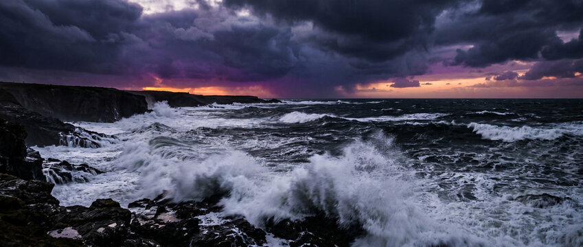 Temp&ecirc;te marine avec vagues d&eacute;cha&icirc;n&eacute;es sur les rochers au coucher du soleil