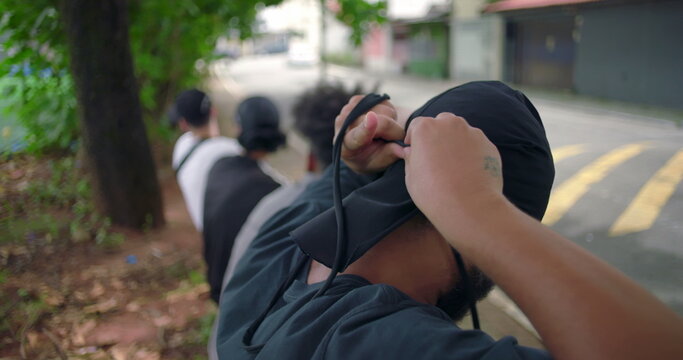 African American man tying durag on head near street and sports field, expressing confidence, cultural pride, and everyday urban style in casual outdoor environment