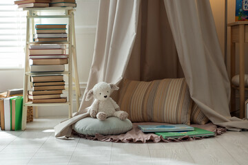 Beautiful wigwam, different toys and books in child's room. Interior design © New Africa