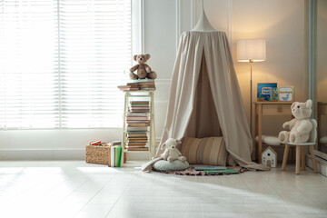 Beautiful wigwam, different toys and books in child's room. Interior design © New Africa